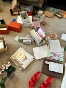 The contents of a cupboard scattered on the floor. There are boxes upside down, piles of debris, and even a pair of red sandals.