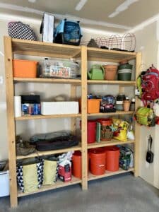 Wide shot of garage shelves. Boxes and bins are stacked neatly, along with pots and potting soil.