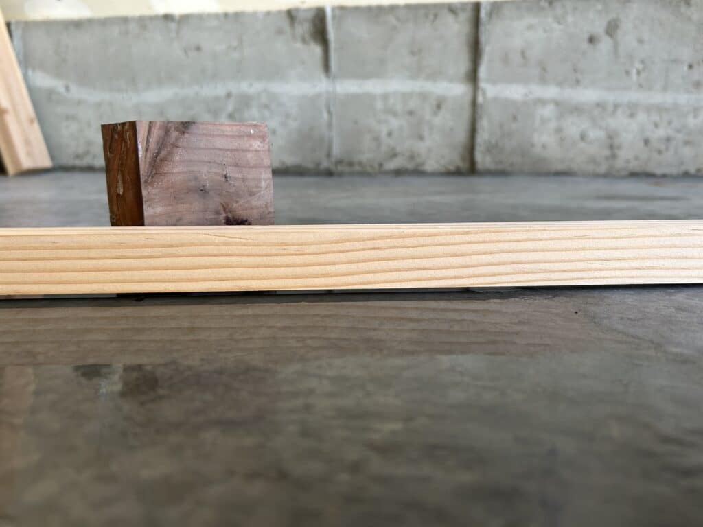 a board sits across a low spot on a cement garage floor. 