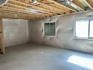 An empty unfinished basement with insulated walls and a south facing window.