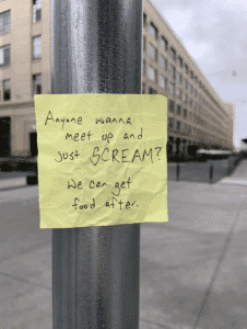 A post it note stuck to a streetlamp. The note says, "Anyone want to meet up and just SCREAM? We can get food after."