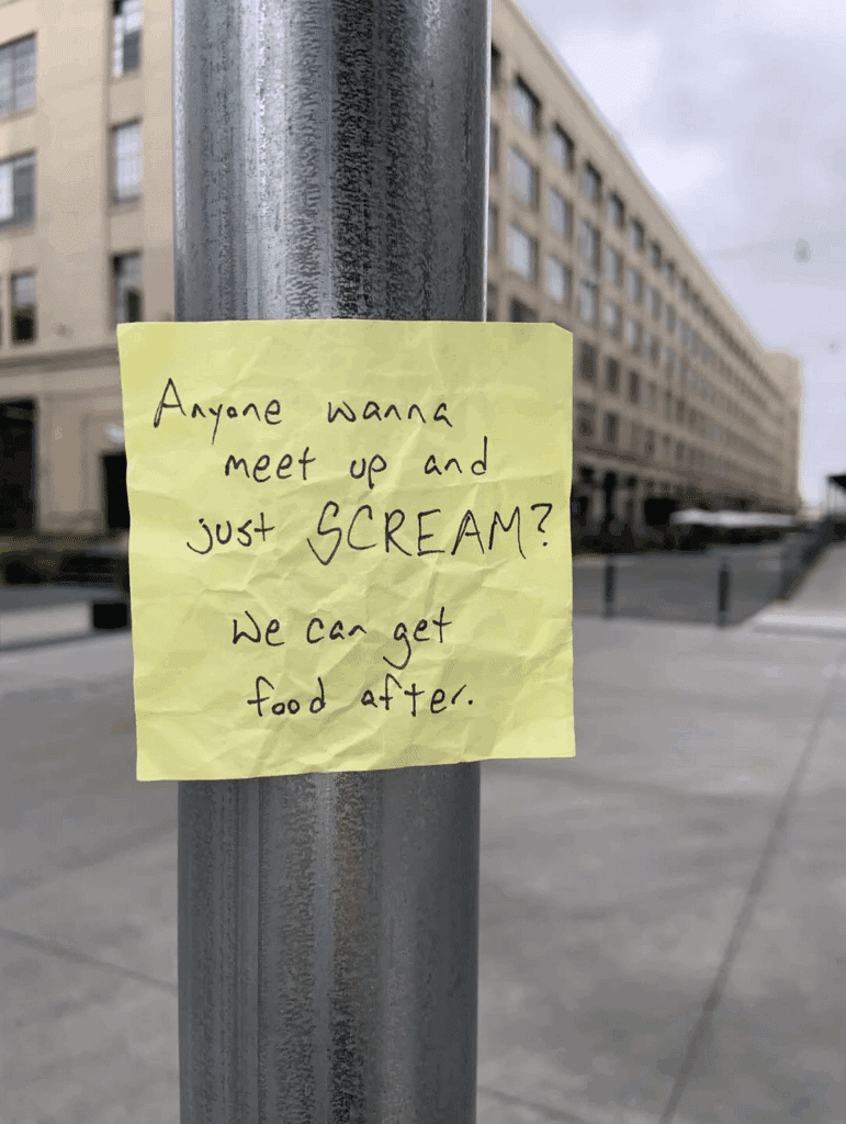 A post it note stuck to a streetlamp. The note says, "Anyone want to meet up and just SCREAM? We can get food after."