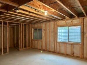 The same unfinished basement with studs over the insulation and a room framed in.
