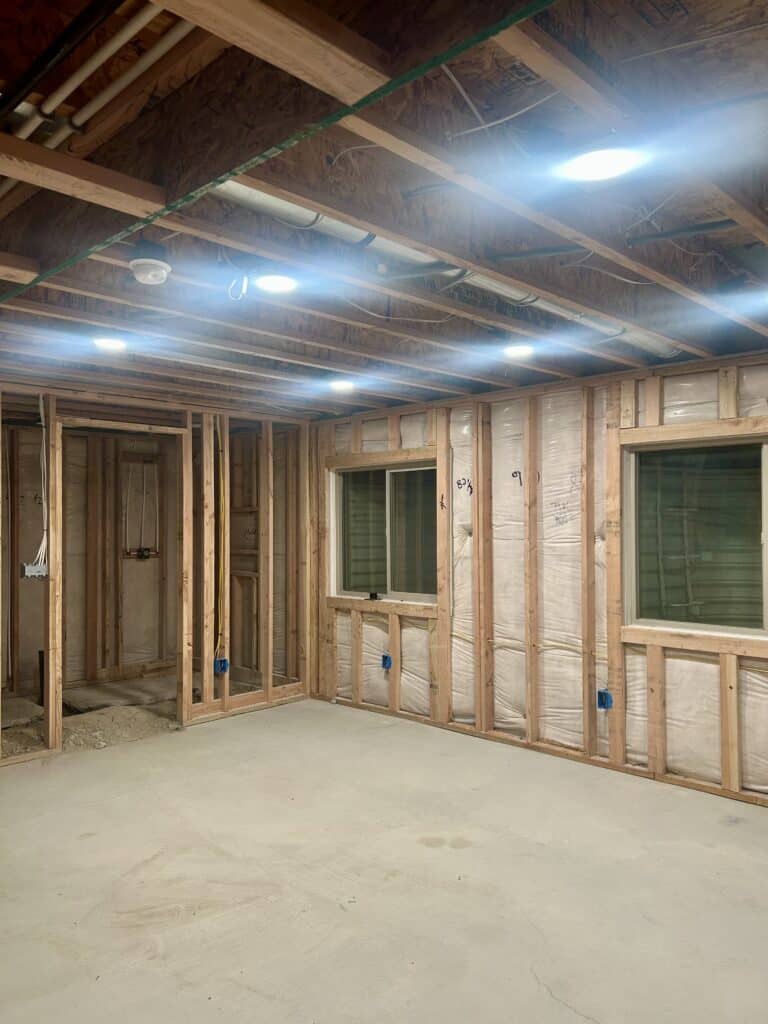 A framed basement with 6 bright lights in the ceiling. 