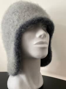 A gray felted hat with long earflaps is displayed on a mannequin head
