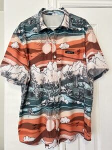 A man's shirt in a scenic desert print in shades of orange and green