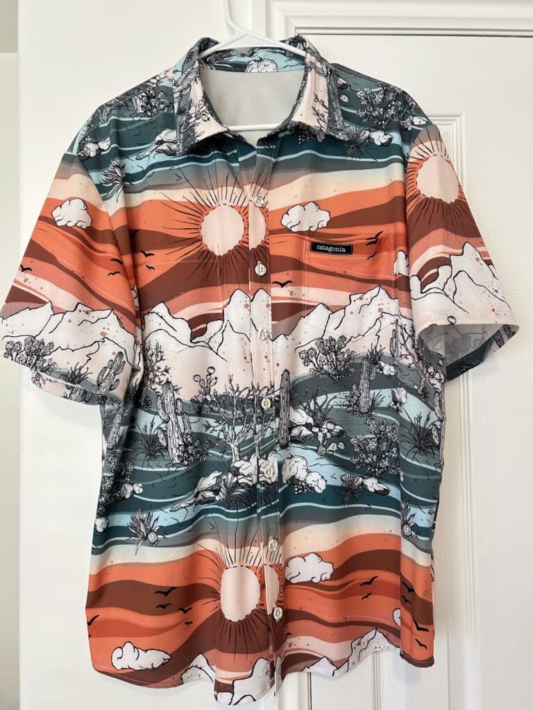 A man's shirt in a scenic desert print in shades of orange and green