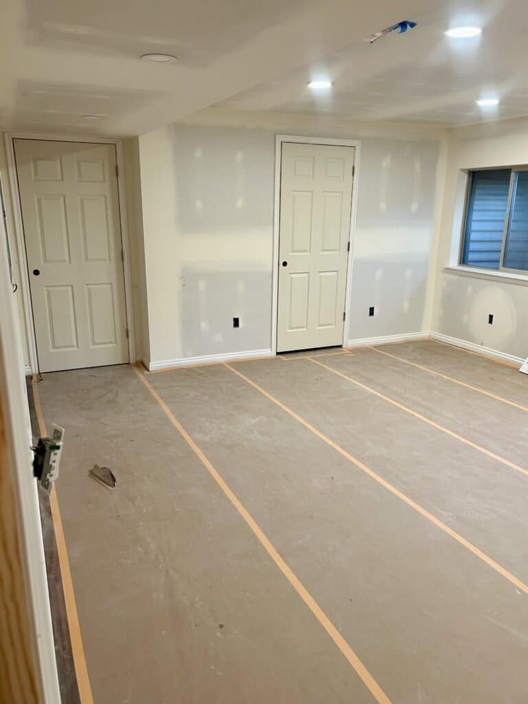 A basement room with two doors at the end of it. 