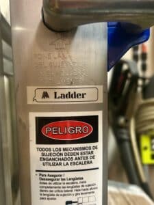 Close up of a warning sticker on a metal ladder, with a label saying "ladder" above it.