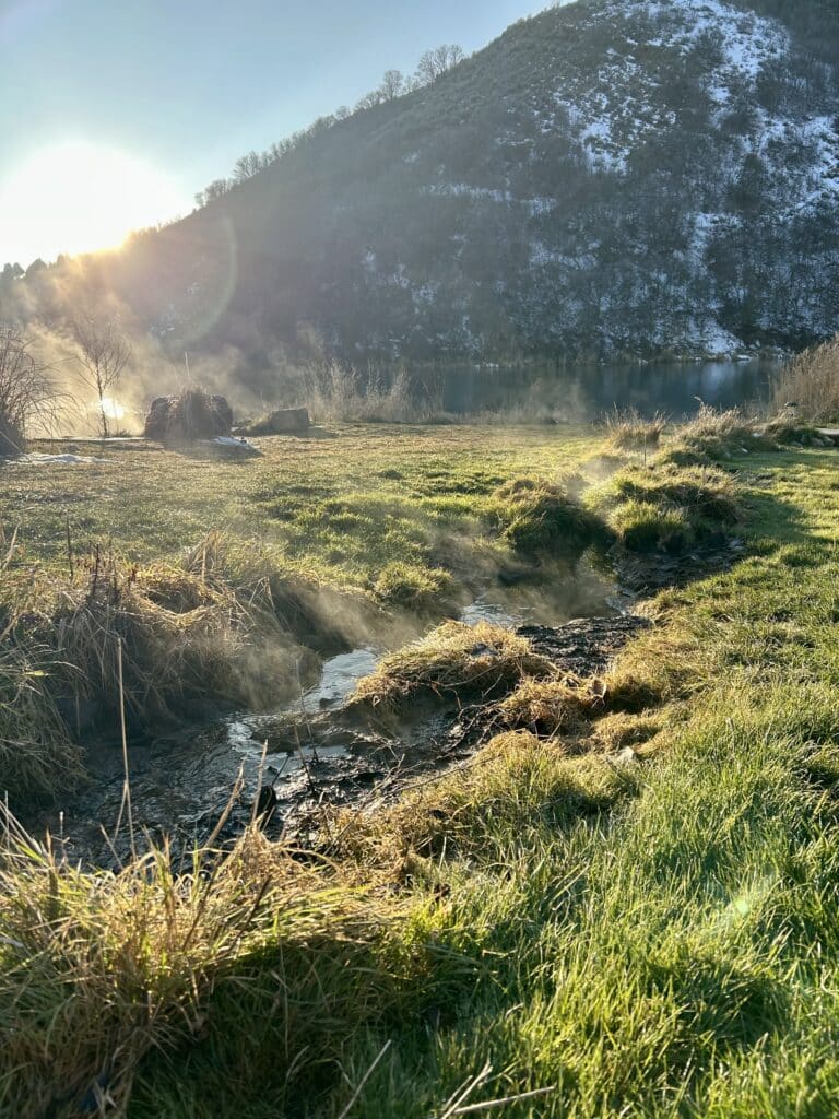 A steaming stream runs down to the river in the afternoon sun 