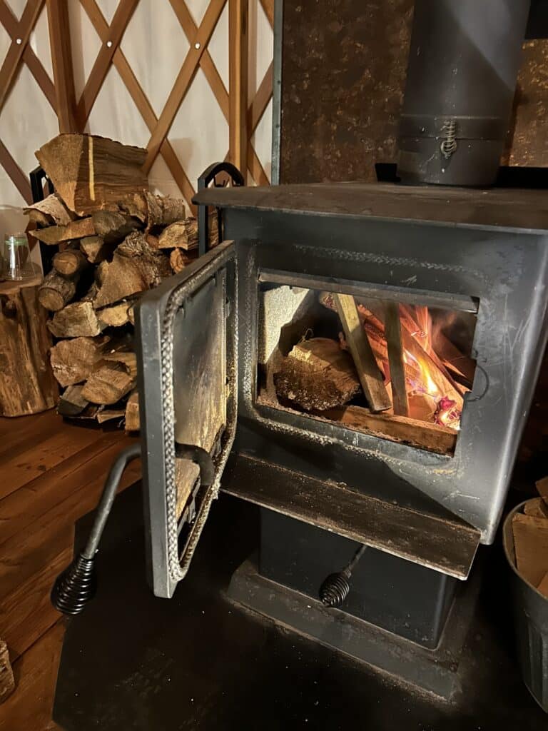 Wood stove in a yurt with the door open to see the fire