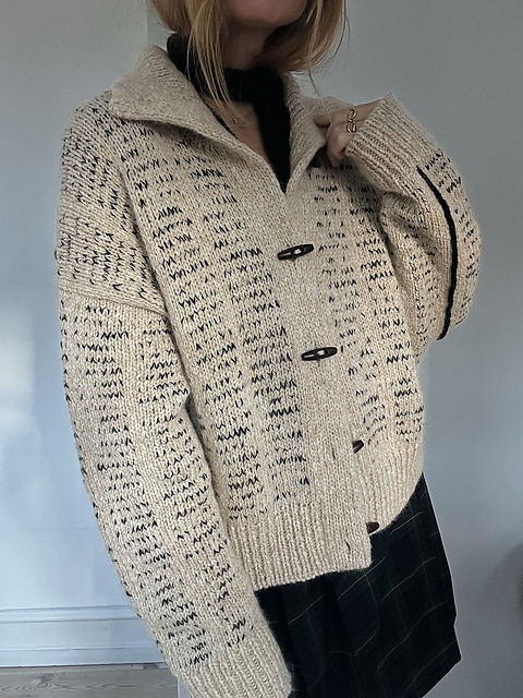 A tan cardigan with black flecks and a floppy collar