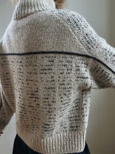 The back of a tan cardigan, with a narrow black stripe running across the back