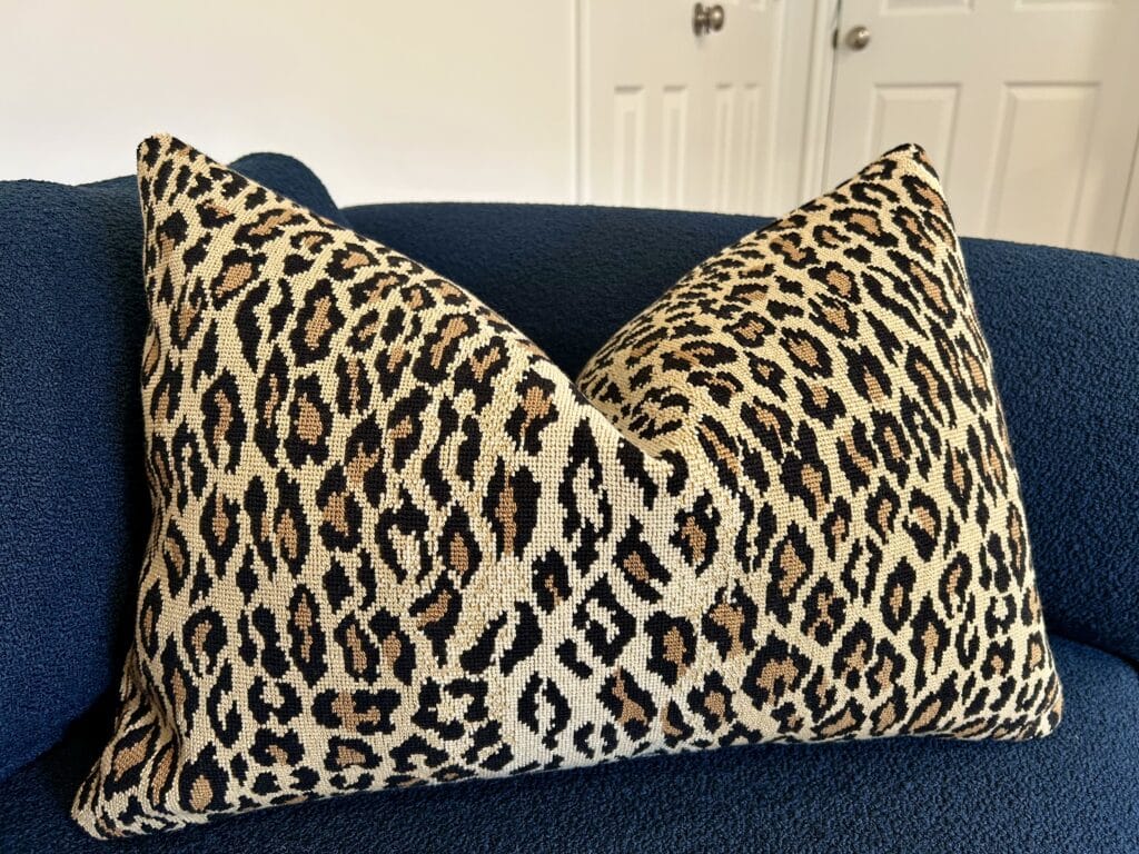 A leopard print oblong pillow on a navy blue couch