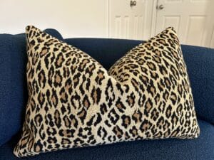 A leopard print oblong pillow on a navy blue couch