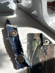 Two fabric scraps with test jeans buttons and test rivets installed
