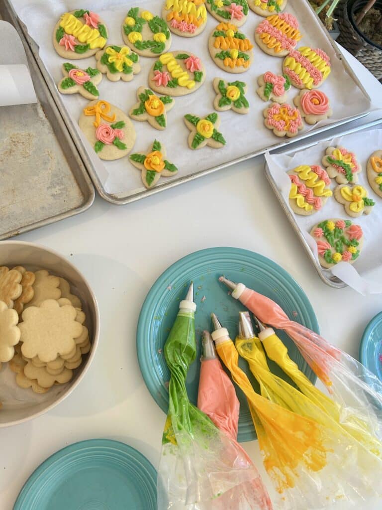 Cookie decorating workstation with 6 piping bags and trays of cookies
