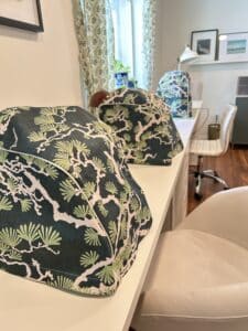 Three covered sewing machines in a row on a long table.