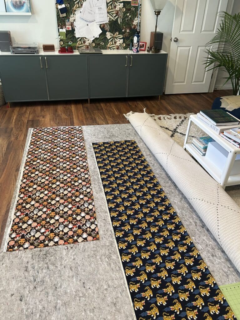 Two lengths of patterned fabric laid out on a rug pad 