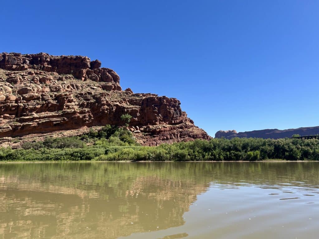 Red cliffs and clear blue sky with the Colorado River in the foreground in Moab 