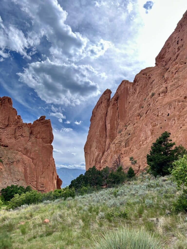Tall red cliffs with blue mountains in the distance in Garden of the Gods 