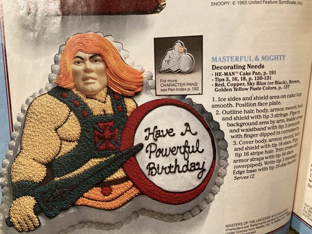 Page from the Wilton book showing a He-Man cake with a shield that says, Have a Powerful Birthday