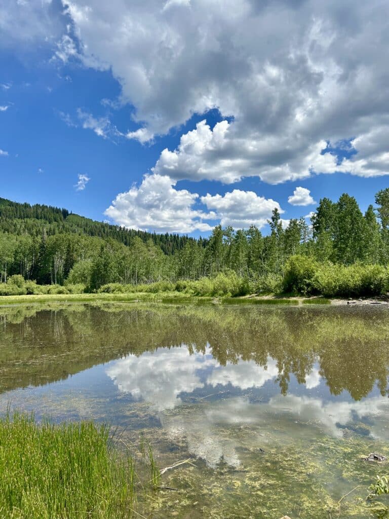 Big white clouds above a mountain lake, reflected in the water 
