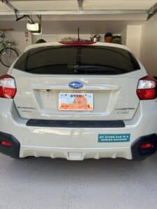 Back view of a tan subaru parked in the garage with a tan floor