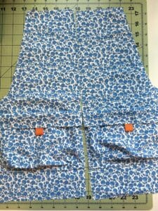 The front pieces of what will be a pair of shorts, with cargo pockets. The fabric is a small blue floral print.