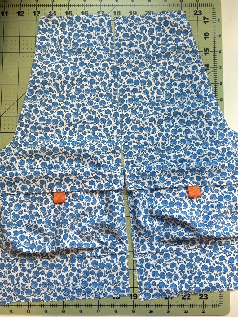 The front pieces of what will be a pair of shorts, with cargo pockets. The fabric is a small blue floral print. 