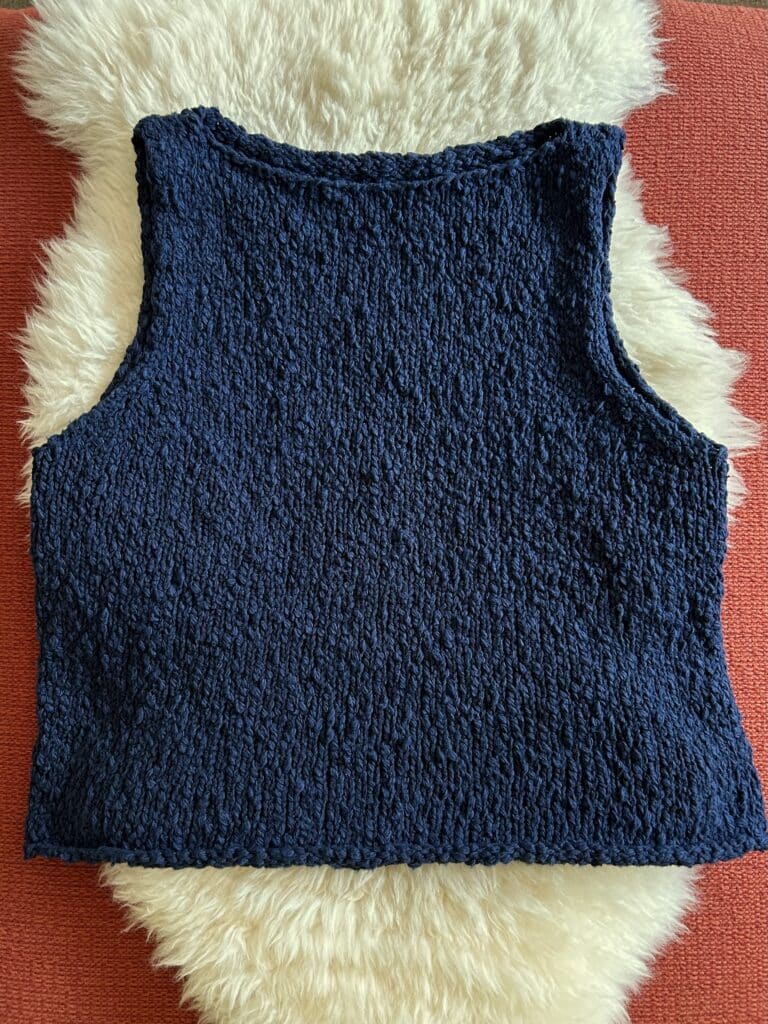 Flatlay of a navy knit boatneck sleeveless top in textured yarn.
