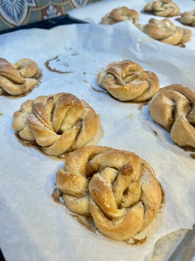 Twisted round cardamom buns on a baking sheet