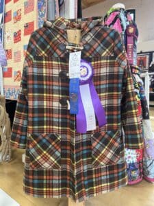 A brown plaid coat with a best of show rosette ribbon and a first place ribbon