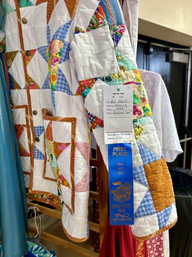 The sleeve of a quilted coat with a blue ribbon on it