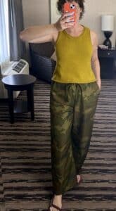 A mirror selfie of a woman wearing an ocher knit tank and camo drawstring balloon trousers