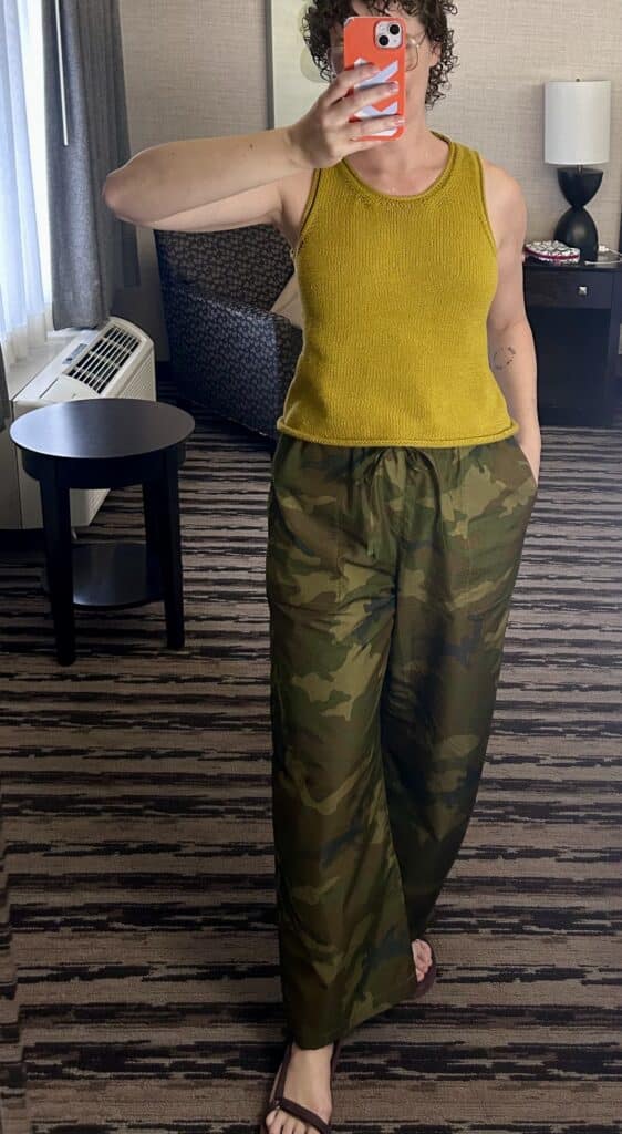 A mirror selfie of a woman wearing an ocher knit tank and camo drawstring balloon trousers 