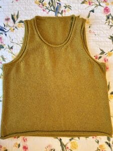 Flatlay of an ocher yellow sleeveless knit tank with rolled trim