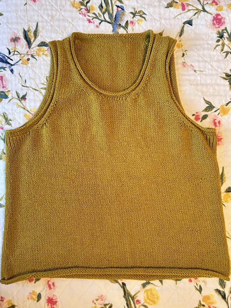 Flatlay of an ocher yellow sleeveless knit tank with rolled trim